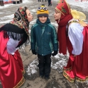 Девушки в русских народных костюмах с маленьким посетителем праздника Масленицы в Сокольниках